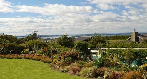 Creating soft curves, planting grasses and flaxes with tropical plants gives movement to this corner